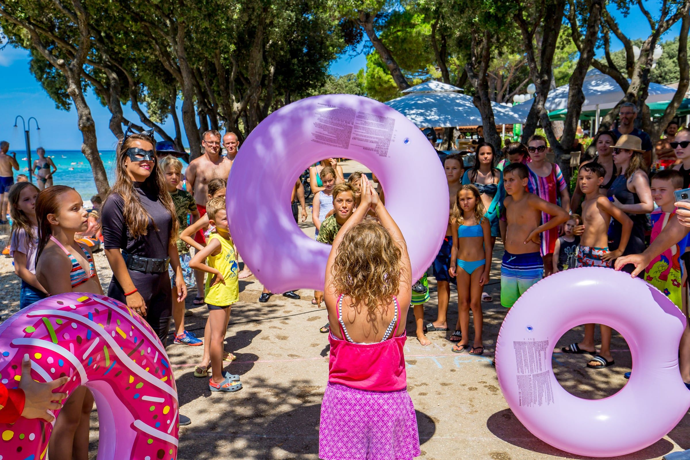 Djeca s ružičastim kolutima za plivanje na animaciji uz plažu